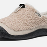 Size profile of a tan fuzzy shoe that has a black rubber sole with a draw string on top against a white background.