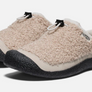 Pair of tan shoes that are fuzzy on the outside with black rubber soles and a draw string on top against a white background.