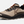 Side view of a tan shoe that has dark brown and burnt orange accents with a large light brown letter K on the side of the shoe.