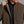 Person holding the collar of a brown jacket.