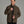 Person wearing a brownish green jacket against a grey background.