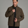 Person wearing a brownish green jacket against a grey background.