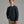 Person wearing a dark blue sweater and khaki pants against a grey background.