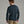 Person wearing a dark blue sweater and khaki pants against a grey background.