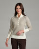 Person wearing a natural colored sweater with buttons against a grey background.