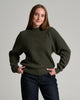 Person in a dark green sweater against a grey background.