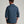 Back view of a person wearing a long sleeve dark blue flannel against a grey background.