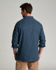 Back view of a person wearing a long sleeve dark blue flannel against a grey background.
