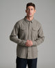 Person wearing a tan colored button up long sleeve shirt.