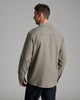 Back view of a person wearing a long sleeve tan shirt with a collar.