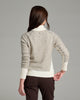 Back view of a person wearing a natural colored sweater against a grey background.