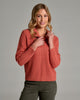 Person wearing a burnt orange sweater and green pants.