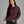 Person wearing a deep purple sweater against a grey background.