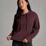 Person wearing a deep purple sweater against a grey background.