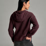 Person wearing a deep purple sweater against a grey background.