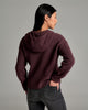 Person wearing a deep purple sweater against a grey background.