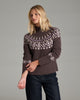 Person wearing a dark purple sweater with dark blue jeans against a grey background.