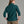 Person wearing a deep teal sweater and khaki pants against a grey background.