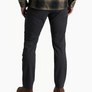Back view of a person wearing dark grey pants with a flannel and brown shoes against a white background.