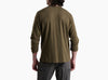 Back view of a person wearing a dark olive green long sleeve shirt and grey pants against a white background.