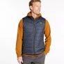 Person wearing a navy colored vest with an orange shirt against a white background.
