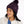 Person wearing a dark purple winter hat with a pom pom on the top in the same color and a light purple tag on the flipped up part of that hat.