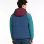 Back view of a person wearing a multi-colored jacket with a hood against a white background.