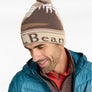 Person wearing a light colored LL Bean winter hat with a blue jacket against a white background.