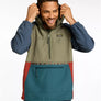 Person wearing a multi colored 1/2 zip jacket holding the hood up against a white background.