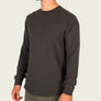 Person wearing a black long sleeve waffle knit shirt against a light grey background.
