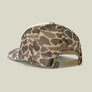 Back view of a snapback hat that is camo against a pale green background.