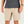 Person wearing beige shorts and a dark shirt on a plain background