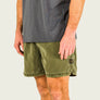 Person wearing green shorts and a gray shirt on a plain background