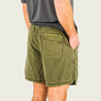 Person wearing green shorts with a pocket on a plain background