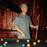 Person wearing a light grey short sleeve button up shirt playing pool