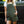 Person wearing green overalls standing next to a black vehicle.