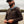 Person wearing a brown 1/4 zip pull over hoodie with nature in the background