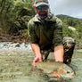 Person wearing a green 1/4 zip hoodie holding a fish in water