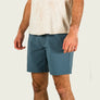Person wearing blue shorts and a light-colored shirt on a plain background