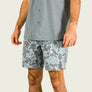 Person wearing a gray shirt and camouflage shorts on a plain background