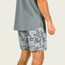 Person wearing a gray shirt and camouflage shorts on a plain background