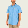 Man wearing a light blue button-up shirt with a logo on a plain background
