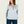 Woman wearing a light blue 1/4 zip pull over sweatshirt with a small logo n the front