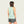 Woman wearing a light green sleeveless top and patterned shorts on a plain background