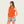 Person wearing a burnt orange tank top with camo shorts against a blank background
