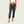 Person wearing dark gray capri pants on a plain background
