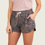 Person wearing camouflage shorts on a plain background