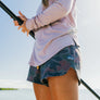 Person wearing a light purple long-sleeve shirt and camouflage shorts with 'Marsh' branding.