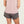 Person wearing a light pink tank top and camo shorts with a black background