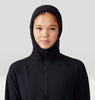 Person wearing a black hooded outfit against a plain background